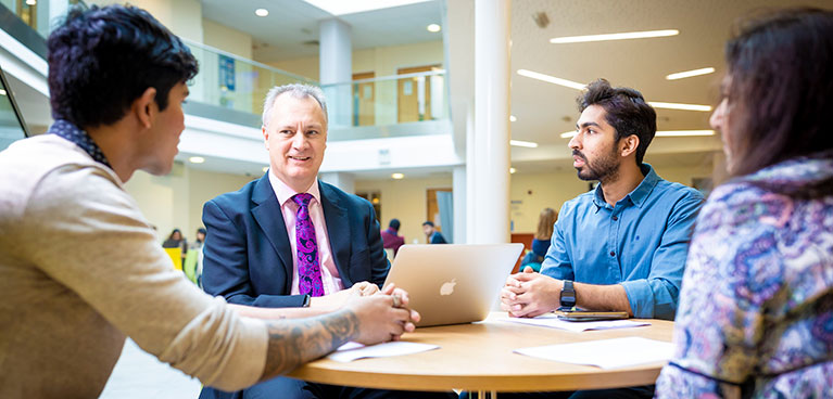 teacher and students sitting at a  table talking
