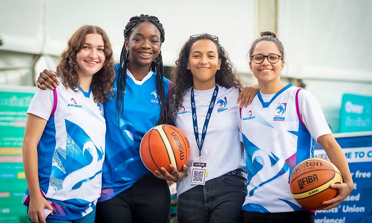 4 young females in sports clothes smiling looking at the camera