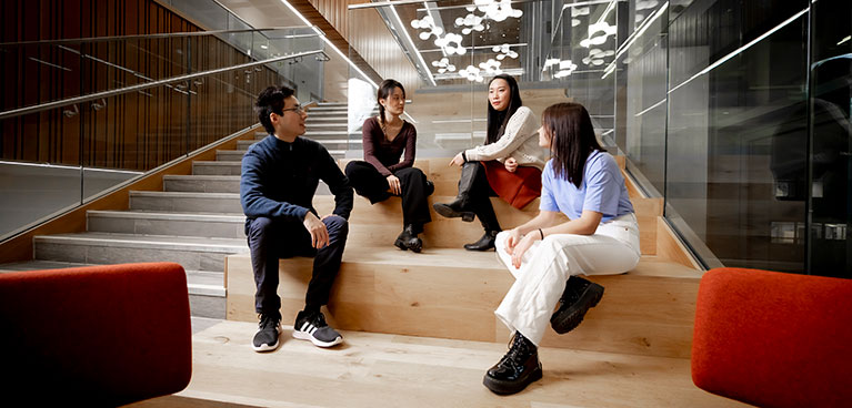 Four students sat on steps talking