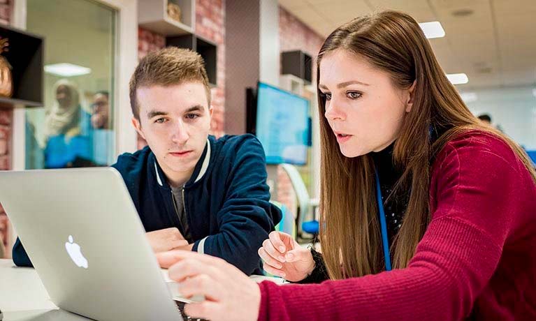 Two students working together on a laptop