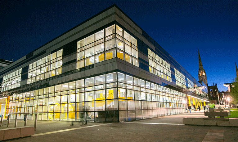 TheHub illuminated at night with church spire in background.