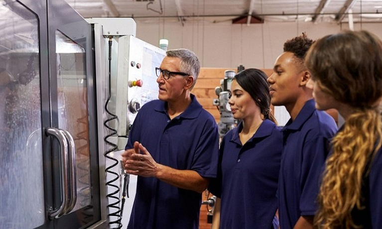 Teacher demonstrating machinery in a workshop