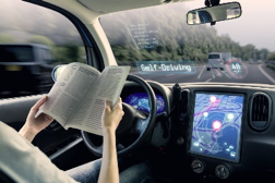 An illustration of someone reading a book in the driver seat of an automated vehicle