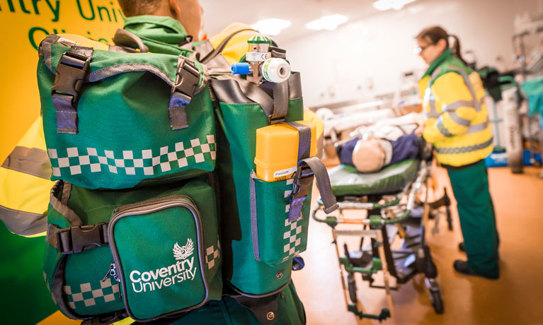Close up shot of a paramedic back pack with a paramedic and stretcher in the background