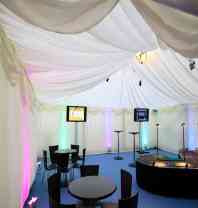 A marquee with a draped material ceiling, bistro table and chairs set up for a party