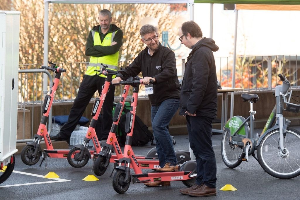 three people look at micro mobility scooters
