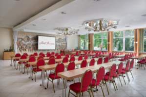 A confrence room in the hotel with rows of tables and red chairs