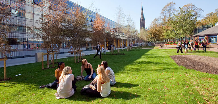 Students sitting on the grass outside a Coventry University building