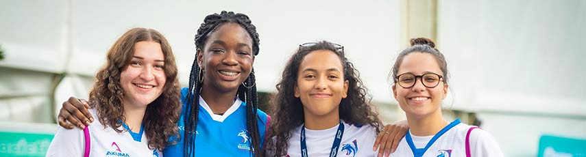 A headshot of 4 young females smiling with arms around each other shoulders