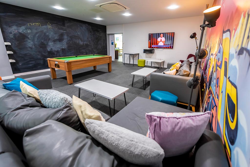 Social room with a chalkboard wall and graffiti wall alongside a pool table and sofa's