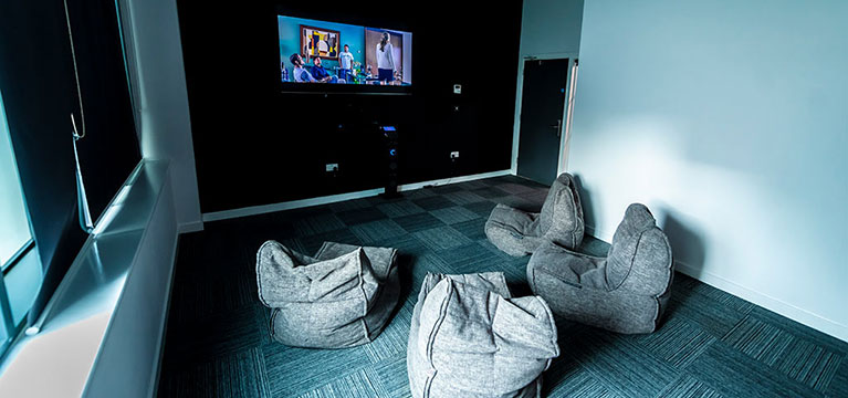 flat screen tv mounted on a black wall in a room of bean bags