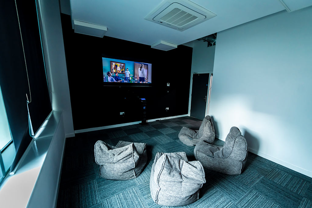 TV mounted on a dark wall with four bean bags