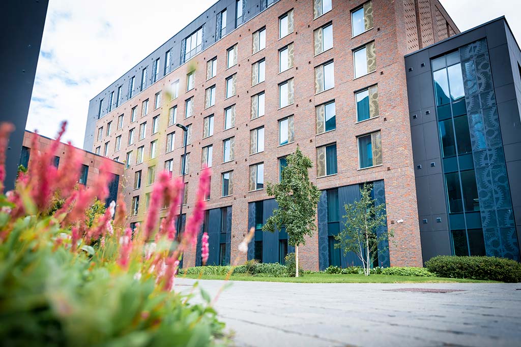 Exterior of Godiva Place student accommodation with pink flowers and trees