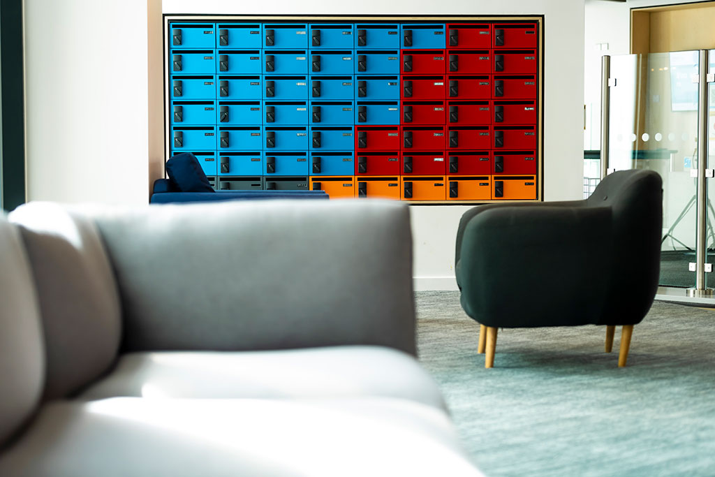 Blue, red and orange lockers mounted on the wall with three individual sofa's