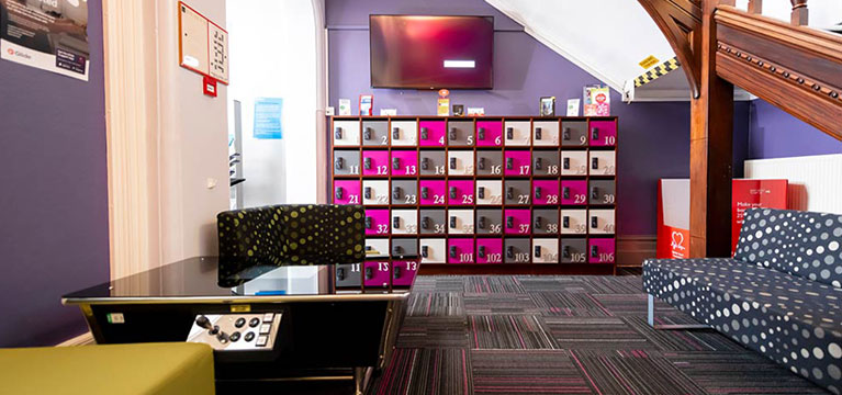 Lobby area in Singer Hall with a games table, wall-mounted tv screen and brightly coloured sofas and lockers.
