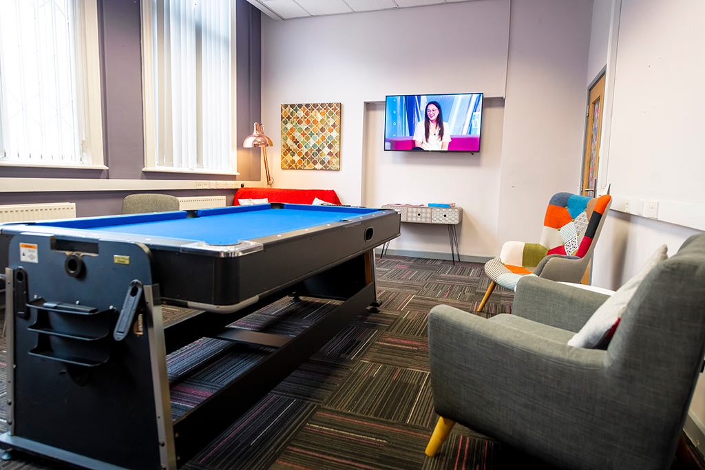 Small room with a pool table, informal seating and a tv mounted on the wall