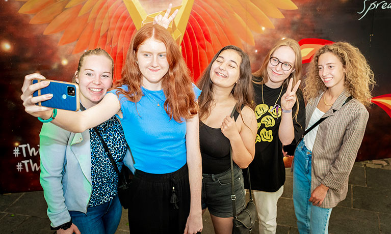 Group of students talking a photo in front of a piece of art