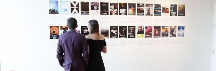 two people standing, facing away from camera, looking at two rows of art