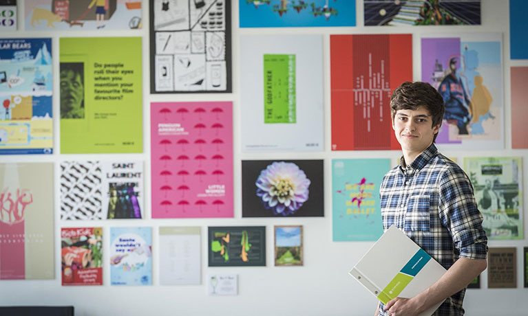 Student in front of wall of graphic design examples