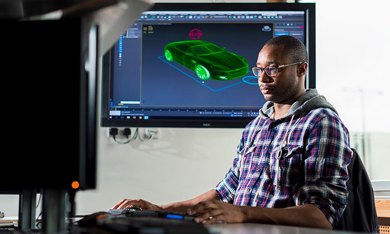 Adult student working on a computer while having a screen in the background