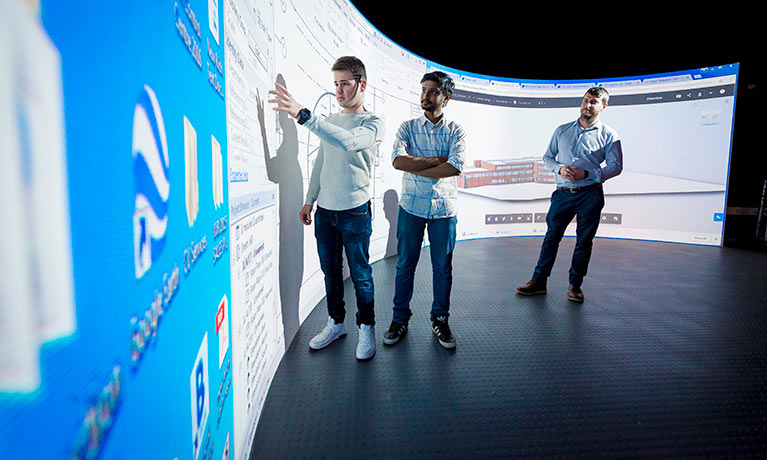 Three students using a virtual wall in the simulation centre.