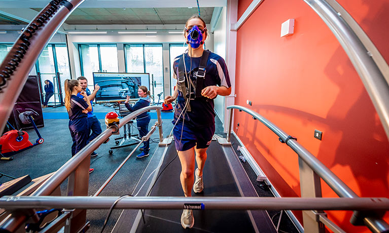 female running on a treadmill with a mask wired up to a machine