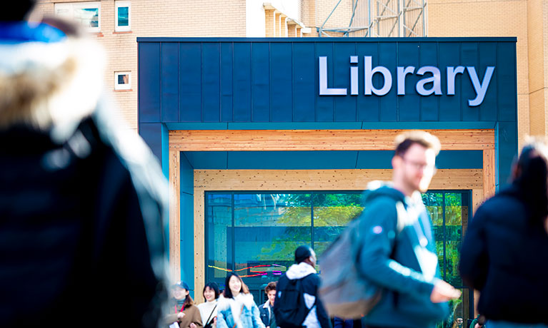Students walking across the library entrance
