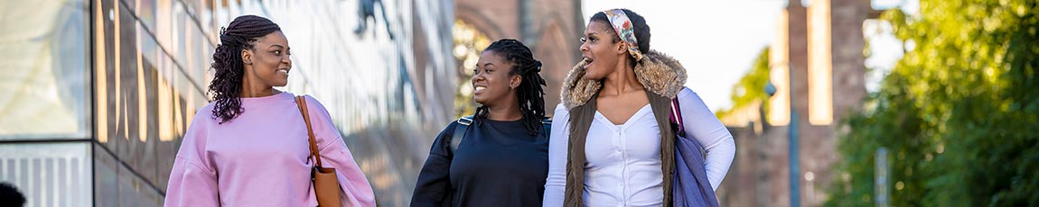 three students walking past the hub talking and laughing