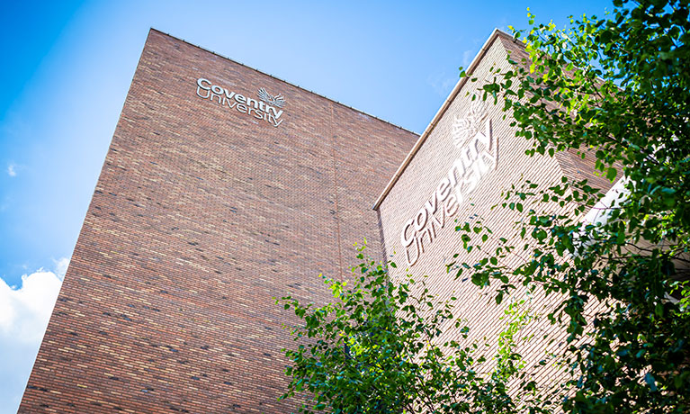 Exterior wall of a tall brick building with the inscription Coventry University