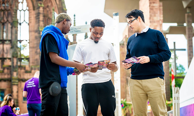 Three young men in the Coventry Cathedral ruins at an open day.