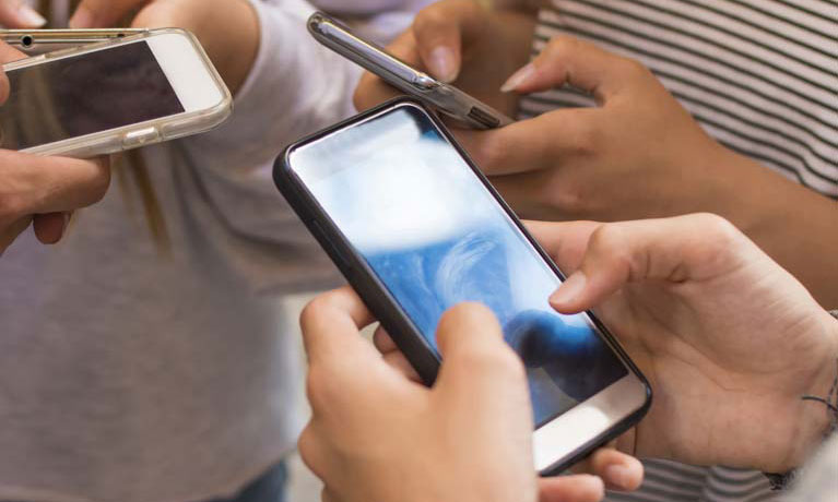 Three students on phones gathered together