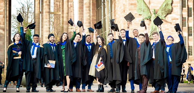 Graduation ceremony at then side of a historic building with lots of students taking pictures