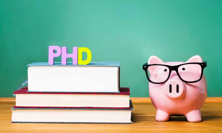 Piggy bank with glasses next to PHD letters on top of three books
