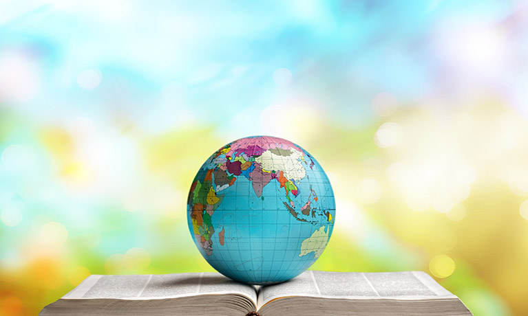 Metal globe placed on an open book on a blurred background