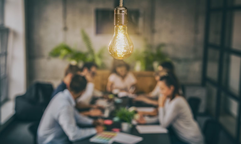 People say around a desk with a light bulb above them