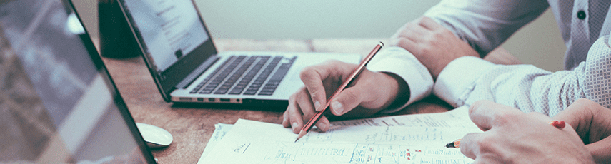 two people calculating finances with a laptop and pen and paper