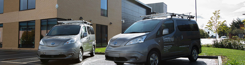 two electric vans sit outside a building