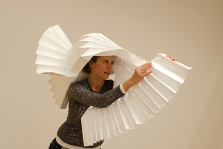A woman performing with a large origami type paper prop