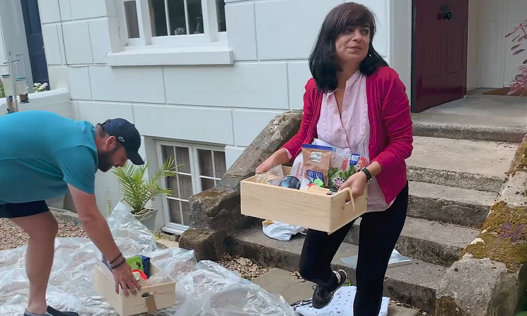 lady in front of house delivering a food box