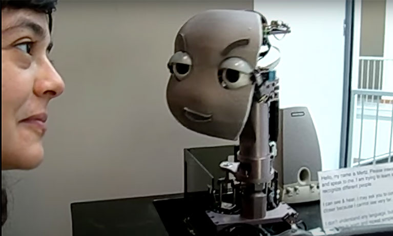 A woman looks at a robot's face