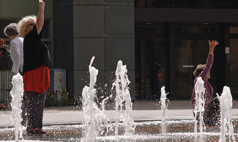 two people dance in a city's fountain