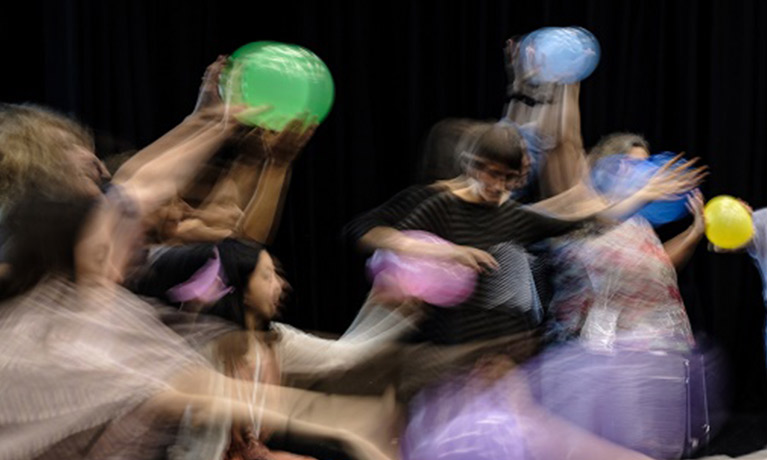 an image of people dancing with balloons blurred by movement
