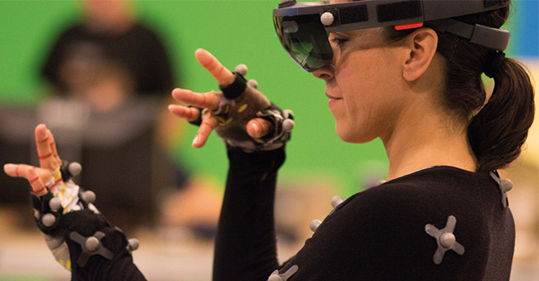 A woman wearing a catsuit dances in front of a green screen