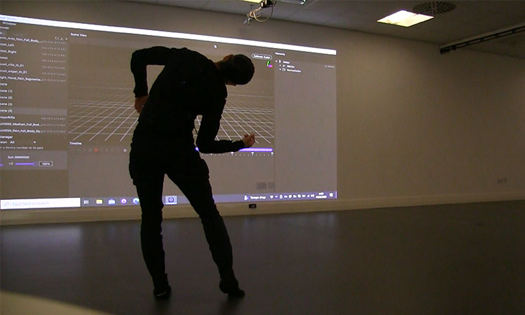 a man bends over dancing in front of a projected screen