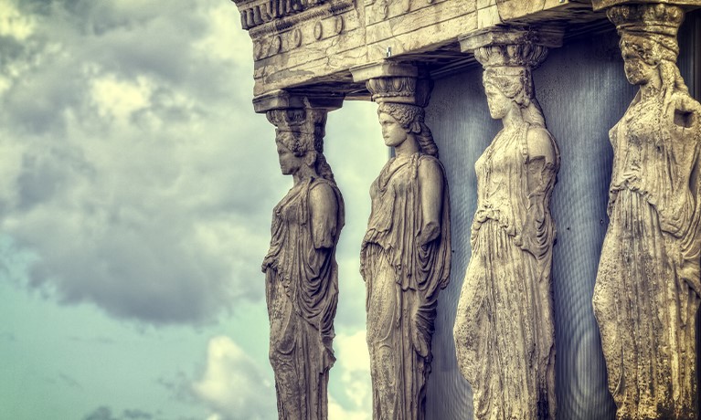 four ancient statues in front of a cloudy sky