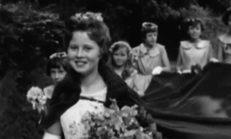 A fuzzy black and white photo of a girl in a procession