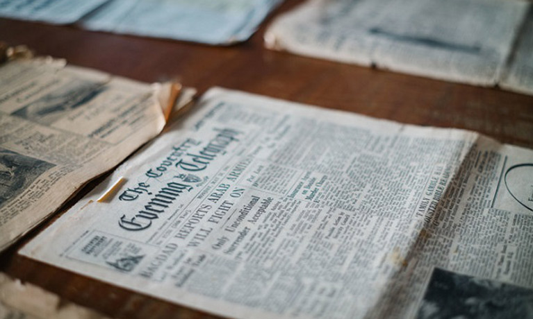 a table has a series of old newspapers laid out on it
