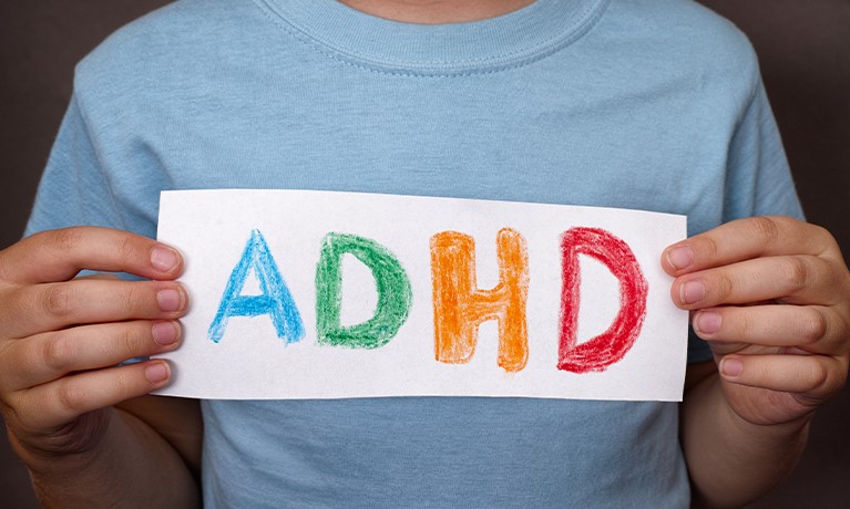 person holding a sign with adhd written in different colours
