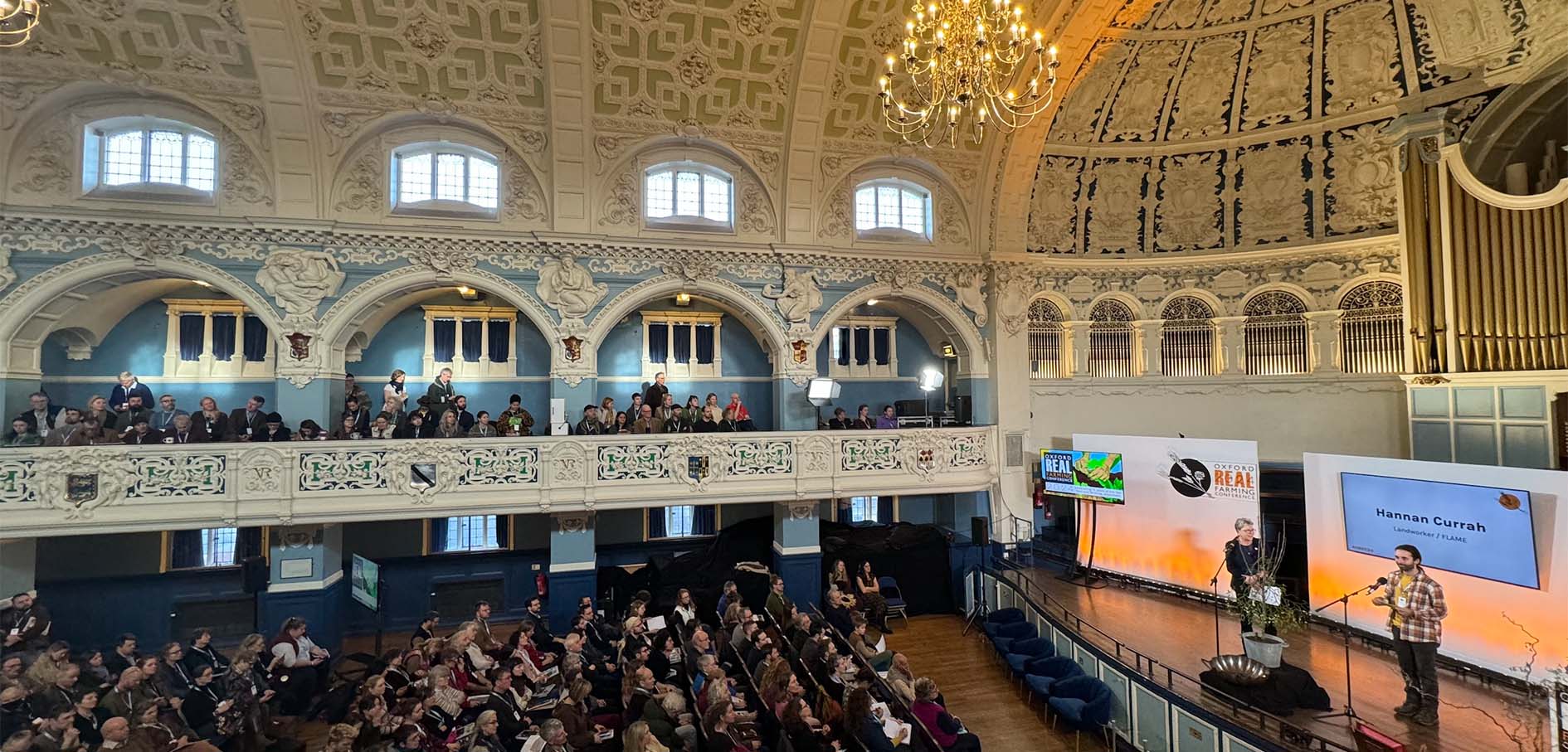 A balcony view of a conference in action, inside a pretty town hall