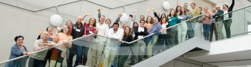 Members of the project are posing for the picture up a staircase with a transparent glass balustrade